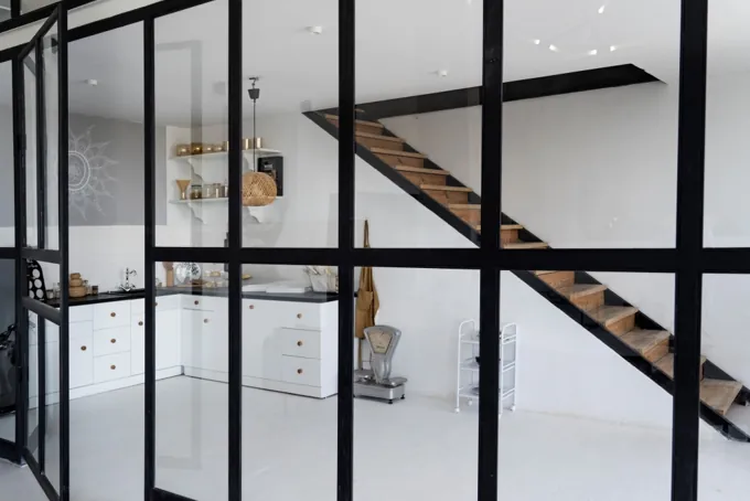 Verrière noire entre une cuisine et un escalier